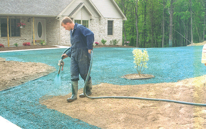 A worker performing hydroseeding in a residential application